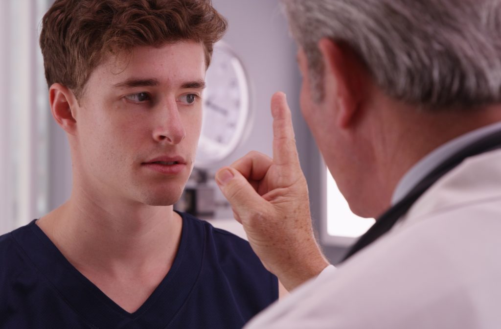 A young male athlete at his optometrist getting his eyes examined after suffering a concussion
